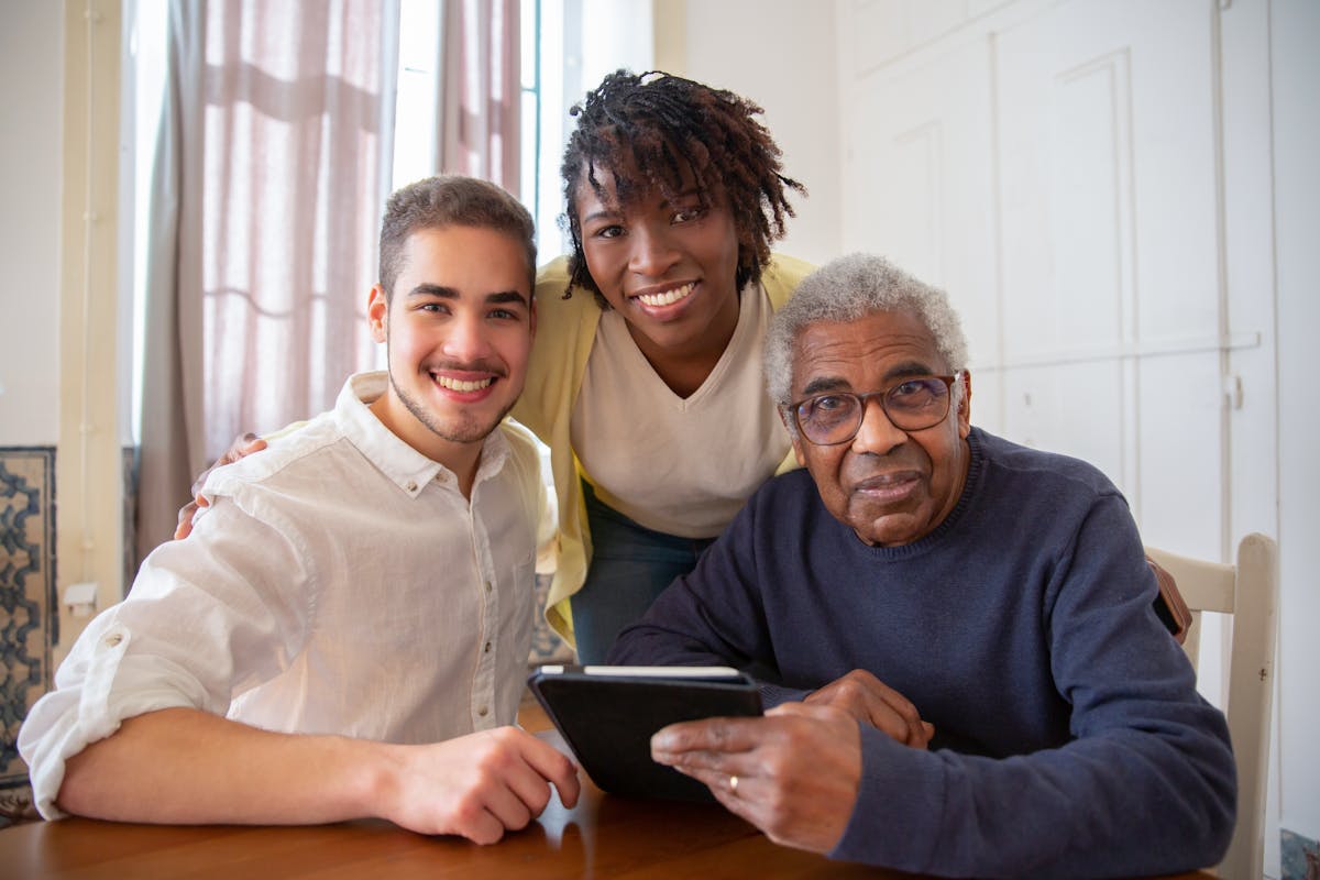 Older adult holding a tablet with two companions beside him
